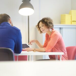 Mitarbeiterzufriedenheit messen durch Einzelgespräche; Bild zeigt sitzende Frau im Gespräch mit Mann